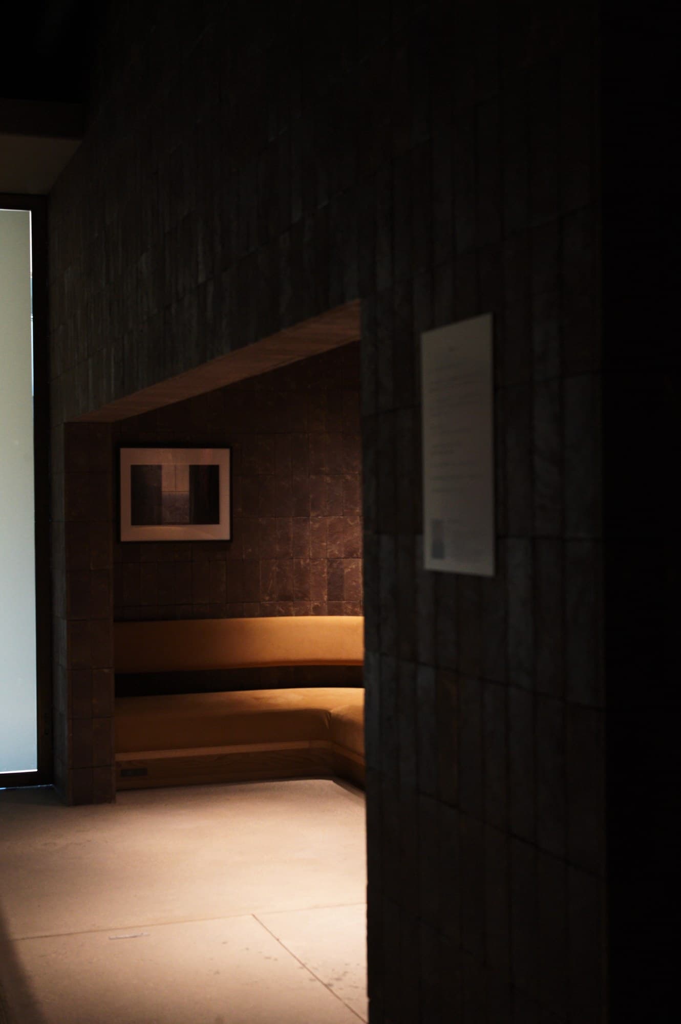 A small alcove in the venue: a work with its wall text beside it, a bench running below