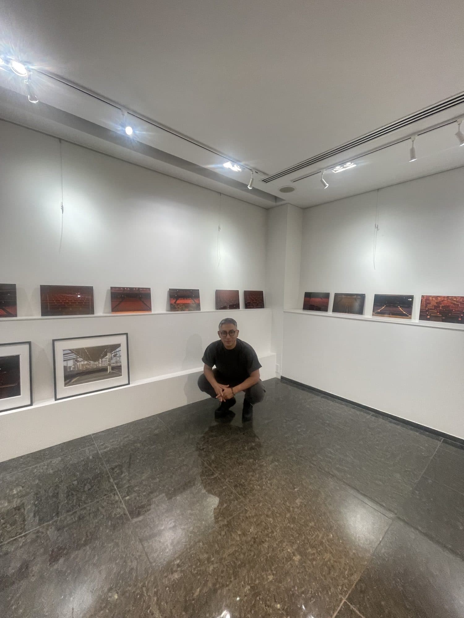 個展会場。壁づたいに客席の連作が並び、下段に額装の作品が掛かる