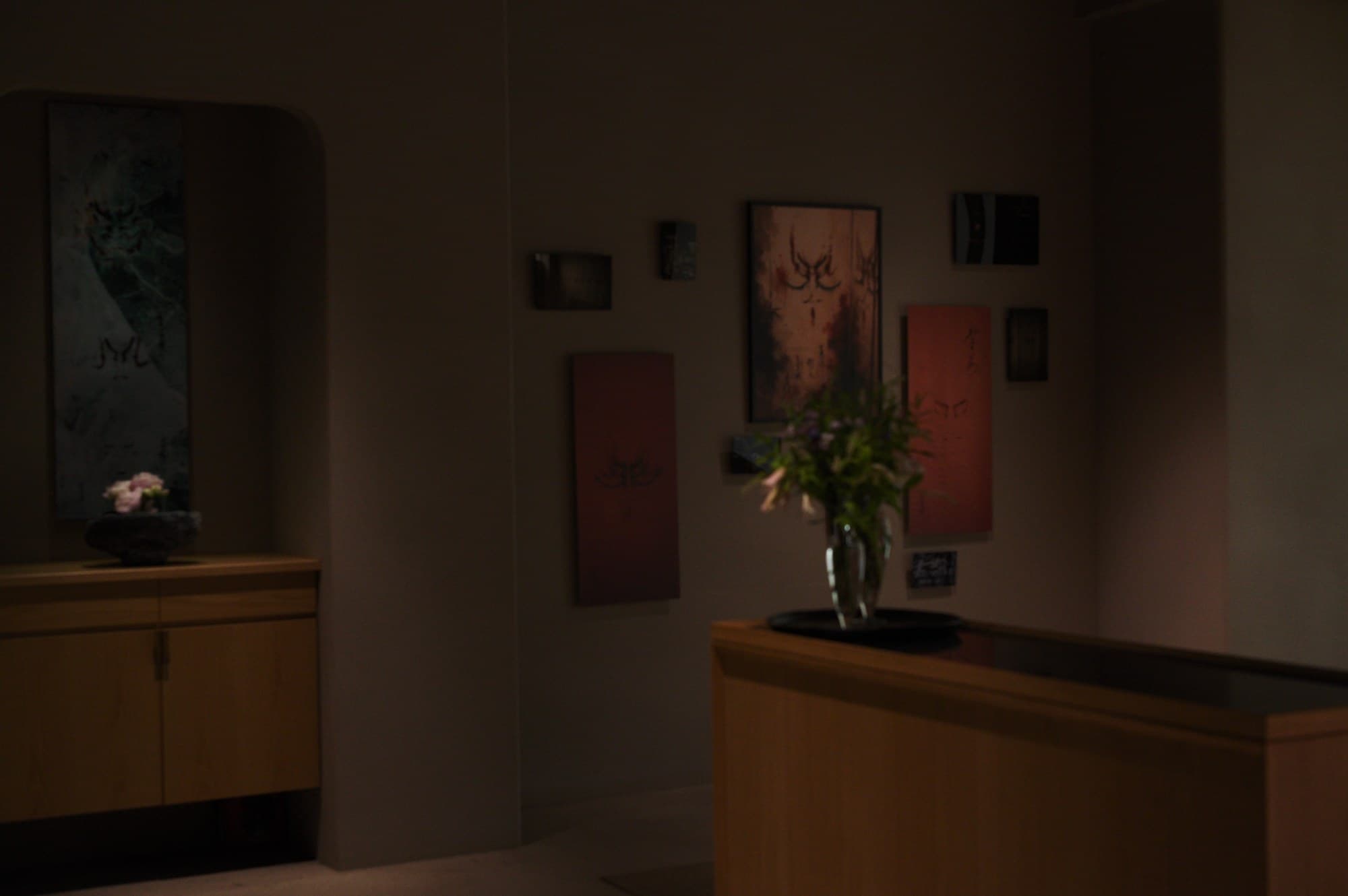 A wide view of the room: the tokonoma-like alcove on the left and the wall of works on red paper on the right, in one frame