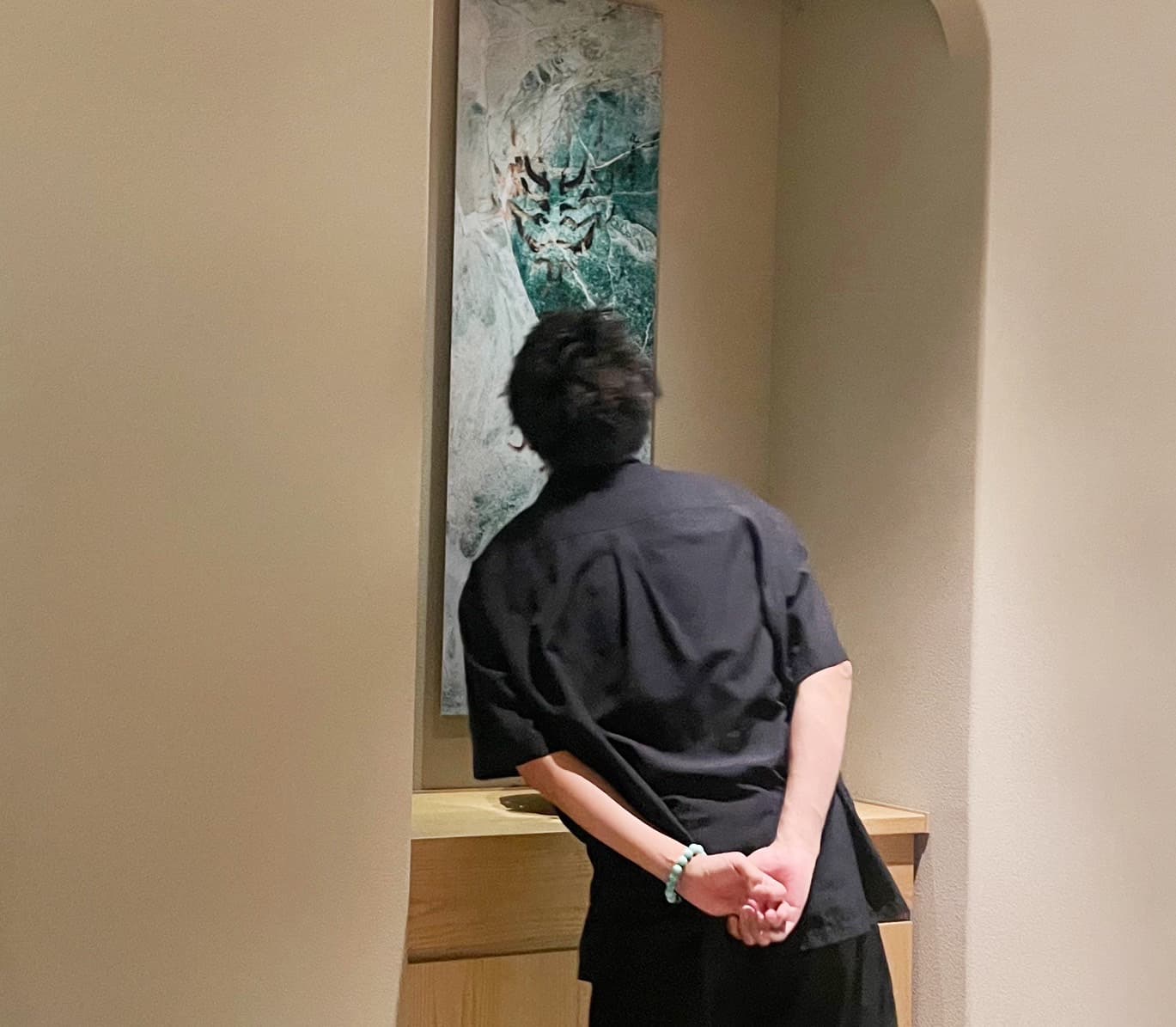 個展会場でターコイズの隈取の作品を見る後ろ姿