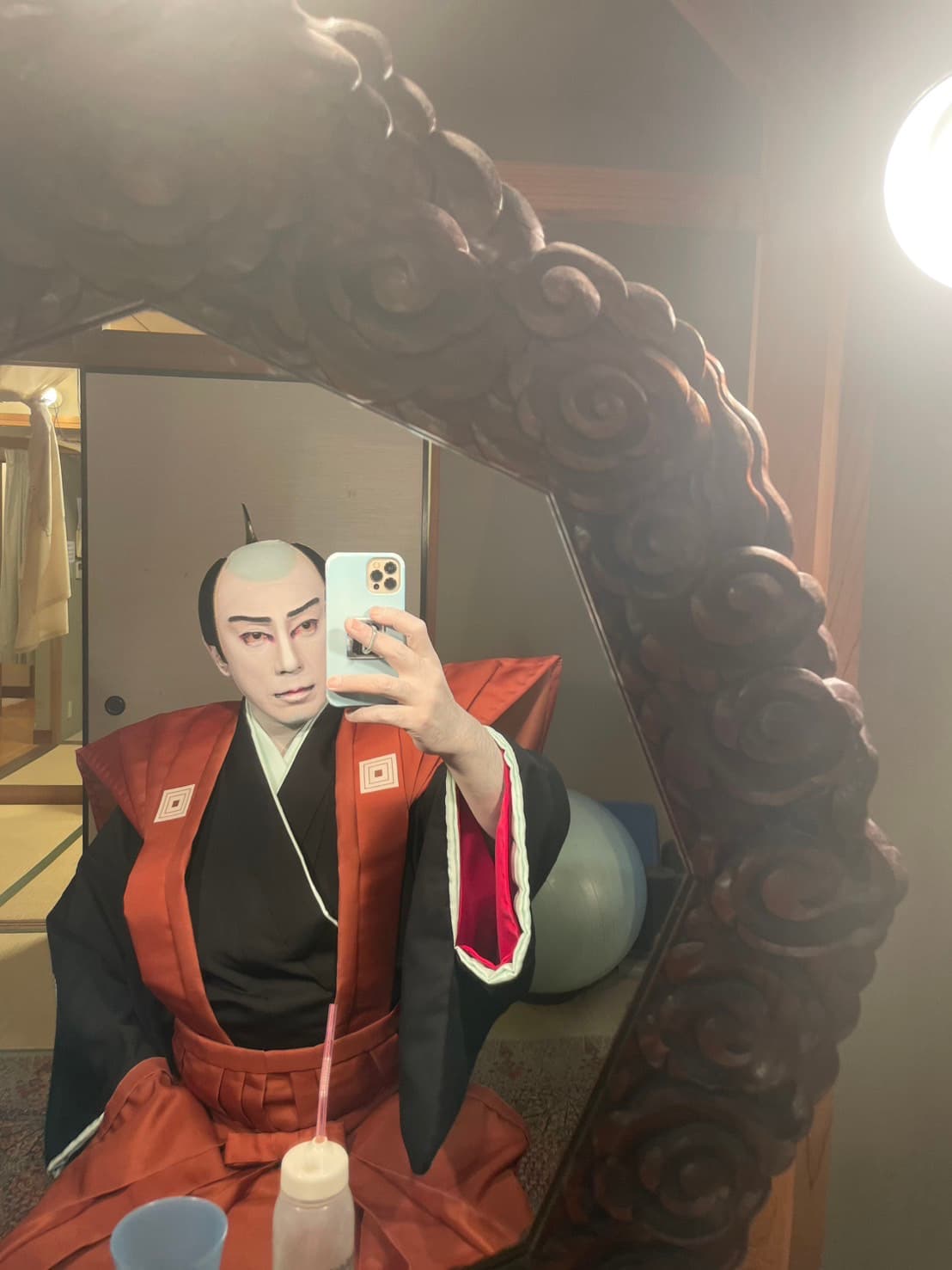 赤い裃姿で楽屋の鏡の前に座る